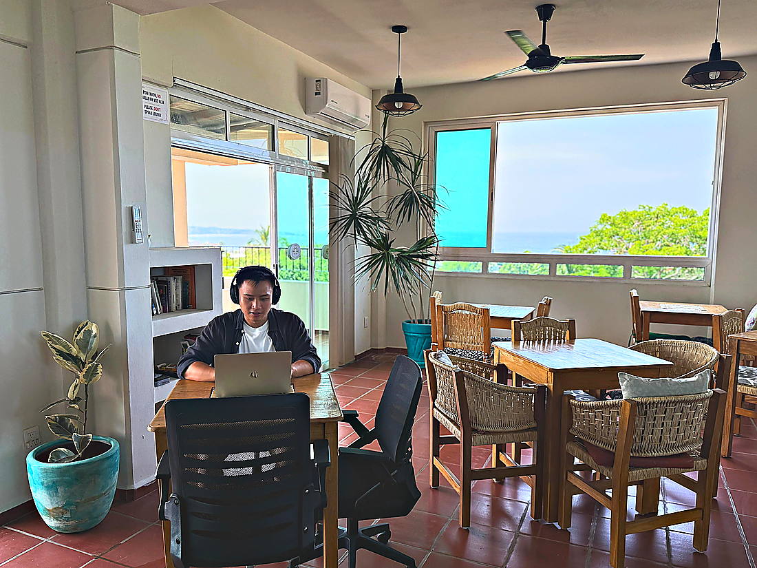 Huésped trabajando en el coworking con el mar de fondo
