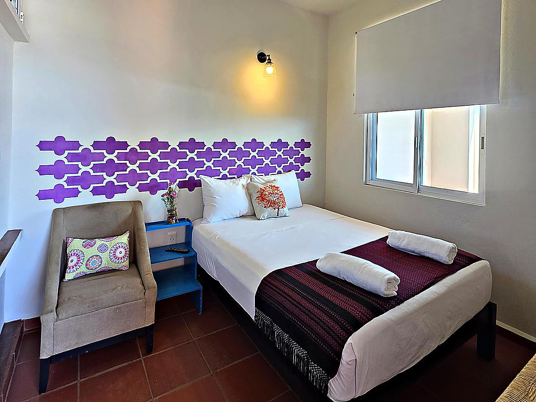 Estudio con cama matrimonial, sofá y cocineta al fondo