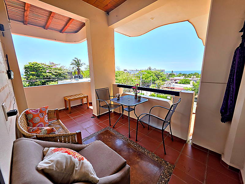Terraza privada con sofá y mesa, el mar al fondo